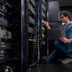 IT engineer kneeling and working on IT network server equipment