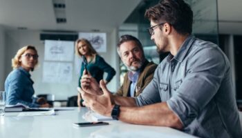 Group of four people in a conference room discussing IT strategy